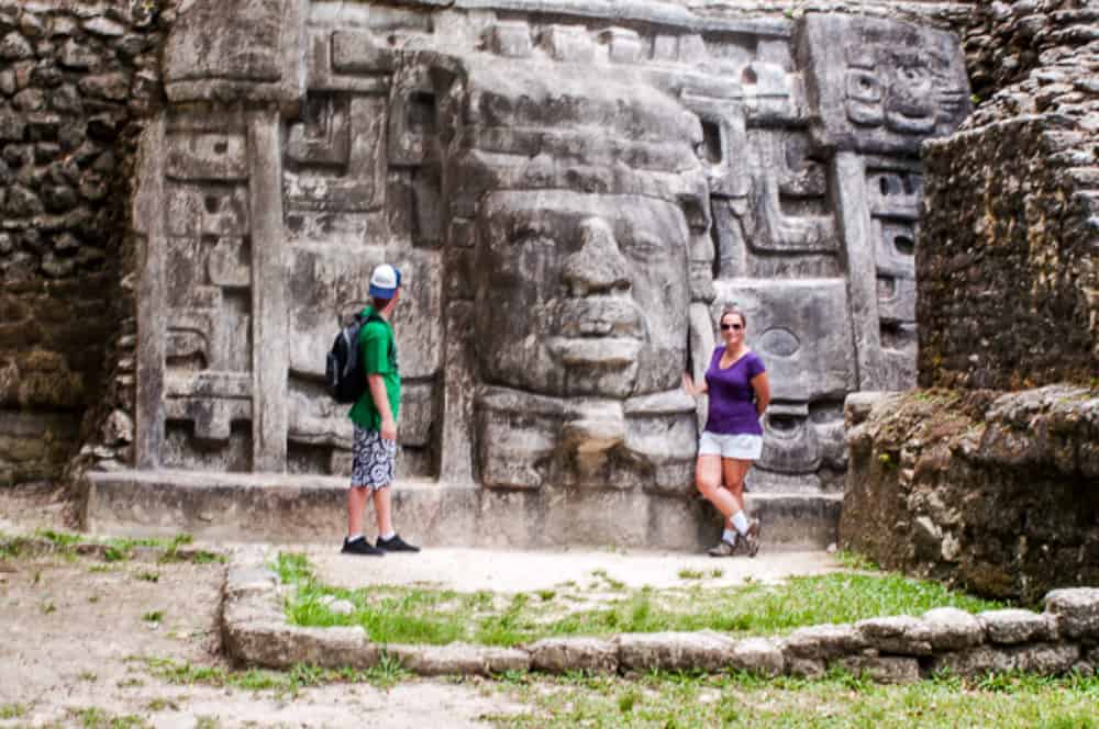 Guests beside the carved mask at Lamanai, Belize