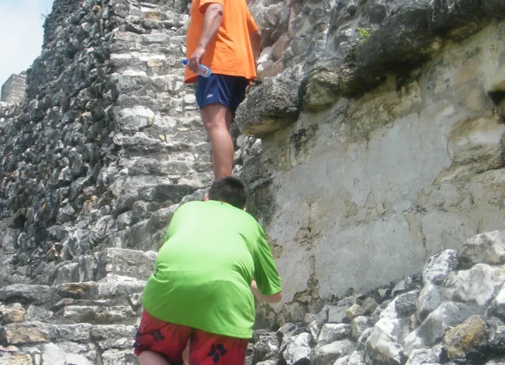 Travelers climbing the stone terraces at Xunantunich Maya ruins in Belize
