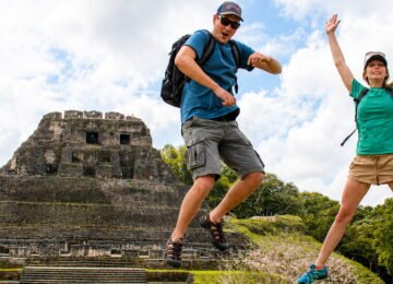 Travelers jumping in front of Xunantunich Maya ruins during a Belize adventure tour