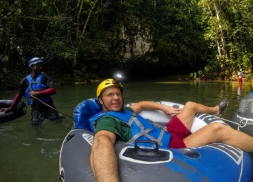 Guest cave tubing with a guide near a Belize cave entrance
